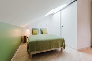 a bedroom with a bed with a green bedspread and yellow pillows at Appart Hotel Neostelia in Annecy