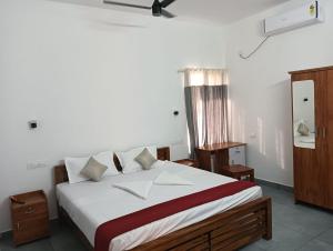 una camera da letto con un grande letto con lenzuola bianche di Captain's Castle a Pallipuram