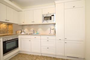 une cuisine avec des armoires blanches, un évier et un micro-ondes dans l'établissement Haus Alice - Segatz 36/2, à Westerland 5 autres photos