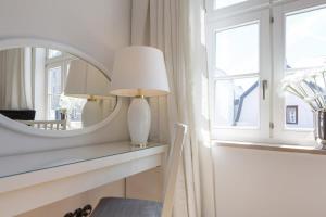 a mirror and a lamp on a table next to a window at Die Schlosserei in Westerland +45 photos