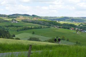 Zwei Personen spazieren auf einem Hügel mit Blick auf ein grünes Feld in der Unterkunft Rhön Ferienwohnung Ebert in Gersfeld