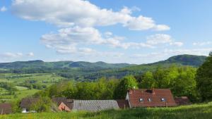 Eine Gruppe von Häusern auf einem Feld mit Bergen im Hintergrund in der Unterkunft Rhön Ferienwohnung Ebert in Gersfeld