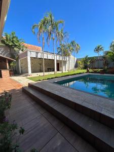 a swimming pool with steps leading to a house at Casa Sa Pedra in Aparecida de Goiânia +6 photos