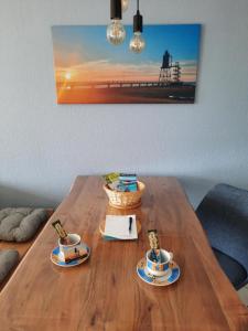 a wooden table with two coffee cups on top of it at Haus Sonnenstrahl 11 in Dorum-Neufeld