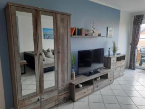 a living room with a large wooden entertainment center with a flat screen tv at Haus Sonnenstrahl 11 in Dorum-Neufeld