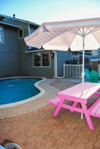een roze picknicktafel met een parasol naast een zwembad bij The Cowboy Cabana in Round Rock