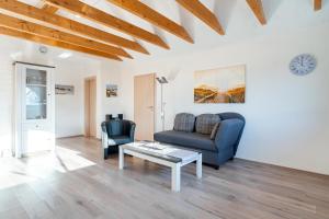 a living room with a couch and a table at Ferienwohnung Seestern mit Rundbogenfenster am Badesee Tannenhausen in Aurich +12 photos