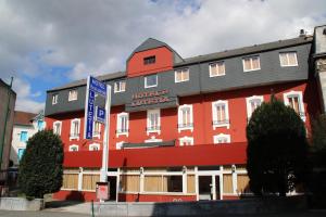 um hotel com um edifício vermelho com um telhado preto em Hôtel Lutetia em Lourdes