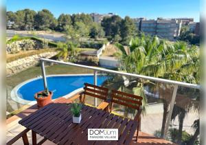 een tafel en 2 stoelen op een balkon met een zwembad bij DOMuum Holidays - PARADISE VILLAGE in Salou
