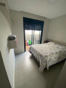 ein Schlafzimmer mit einem Bett und einer Tür zu einem Balkon in der Unterkunft Casa na praia in Xangri-lá + 10 Fotos