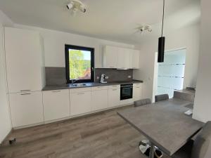 a kitchen with white cabinets and a table and a window at Ferienhaus Residenz am Stausee in Schotten +12 photos