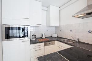 a white kitchen with white cabinets and a sink at Windeby 7T in Wenningstedt