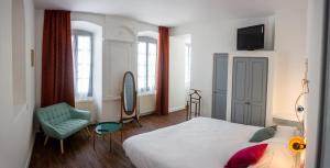a bedroom with a bed and a chair and a television at Hôtel Candide in Saint-Bertrand-de-Comminges