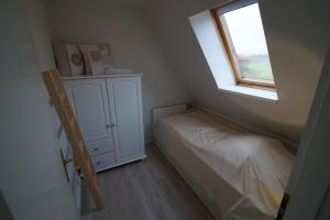 a small bedroom with a bed and a window at FeWo Leuchtfeuer in Grödersby