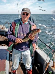Un uomo in piedi su una barca con un pesce di Sternenhimmel a Klausdorf