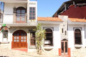 a white house with red doors and windows at Posada San Jorge in Cuetzalán del Progreso