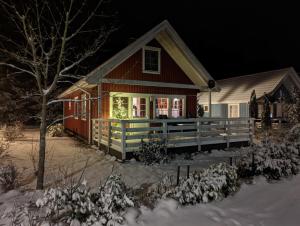a red house with a porch in the snow at night at Villa Rosenrot am See in Userin