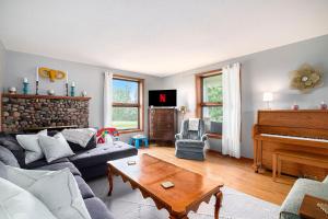 een woonkamer met een bank en een piano bij Historic 5BDR Orchard Home in Suttons Bay +37 foto's