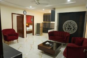 a living room with two red chairs and a table at hotel Elites Residency in city center , iqbal town in Lahore