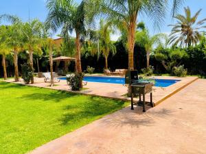 a backyard with a pool and a grill and palm trees at Villa Marrakech, 15 min from center, Disco, Hammam in Marrakesh