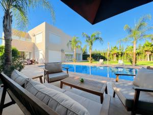 a patio with a couch and chairs next to a swimming pool at Villa Marrakech, 15 min from center, Disco, Hammam in Marrakesh