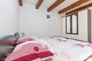 a bedroom with a bed with red and white sheets at Apartman Monkovic in Mokošica