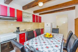 kuchnia ze stołem, krzesłami i czerwonymi szafkami w obiekcie Apartman Monkovic w mieście Mokošica