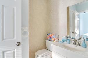 a white bathroom with a toilet and a sink at Walk to Madeira Beach Family Resort Condo in St Pete Beach +16 photos