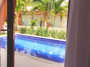 Una vista de una piscina a través de una ventana. en Pousada Sol e Mar, en Maragogi