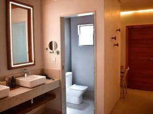 a bathroom with a sink and a toilet and a mirror at Pousada Sol e Mar in Maragogi