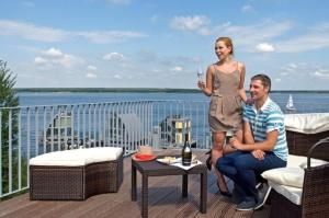 a man and woman sitting on a deck with a glass of wine at Appartment Düne 7 2OG Grundbelegung 2 Pers in Elsterheide