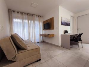 a living room with a couch and a desk with a laptop at Ap 2Q Beira-Mar ao lado do Food Park Cabo Branco in João Pessoa