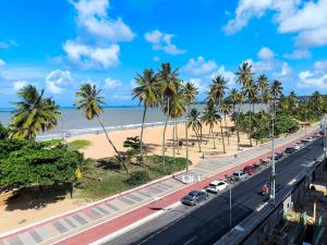 a road with cars parked on it next to a beach at Ap 2Q Beira-Mar ao lado do Food Park Cabo Branco in João Pessoa