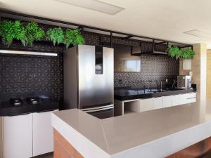 a kitchen with stainless steel appliances and plants on the wall at Ap 2Q Beira-Mar ao lado do Food Park Cabo Branco in João Pessoa