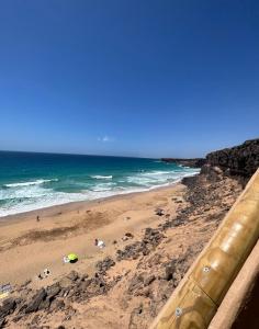 una spiaggia con gente sulla sabbia e l'oceano di Casa Lucia 2 a Cotillo