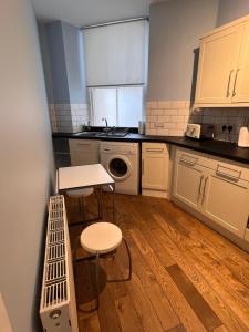 une cuisine avec des armoires blanches, une table et un évier dans l'établissement John Knox's Apartment on Edinburgh's Royal Mile, à Édimbourg