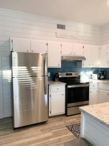 a kitchen with a stainless steel refrigerator and white cabinets at Coastal Condos on the Marsh 6A in Dauphin Island