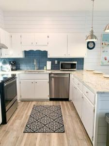 a kitchen with white cabinets and a rug on the floor at Coastal Condos on the Marsh 6A in Dauphin Island