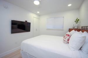 a white bedroom with a bed and a television at Breathtaking Gulf Views Sandalfoot Condo Sanibel Island 3A3 in Sanibel