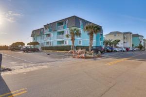 a parking lot with a blue building and palm trees at Balcony with Ocean Views Carolina Beach Condo! in Carolina Beach