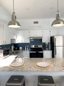 a kitchen with white cabinets and a counter with two stools at Coastal Condos on the Marsh 6B in Dauphin Island