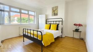 a bedroom with a bed with yellow pillows at 4 Bedroom House with Garden & Parking in Ruislip in South Ruislip Station