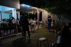 een groep mensen die 's nachts buiten een restaurant staan bij Gen Viajero Hostel in Merlo