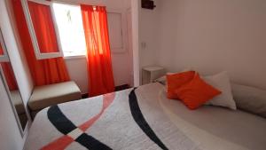 een slaapkamer met een bed met een oranje kussen en een raam bij Gen Viajero Hostel in Merlo +35 foto's