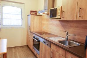 メッペンにあるFamilienhof Brüning - Ferienwohnung Hofblickのキッチン(木製キャビネット、シンク、電子レンジ付)