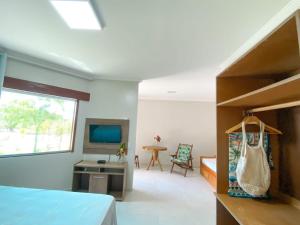 a bedroom with a bed and a desk and a television at Corumbau Recanto dos Pássaros in Corumbau