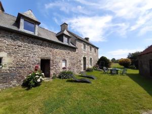 a stone house with a green yard with benches at La maison de Francine in Plouézec