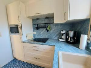 a kitchen with white cabinets and a blue counter top at Komfortferienwohnung Leuchtturm in Sassnitz +7 photos