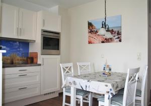 cocina con mesa de comedor y armarios blancos en Strandgut, en Sassnitz