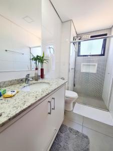 a white bathroom with a sink and a toilet at Loft aconchegante próximo ao Capivari in Campos do Jordão +62 photos